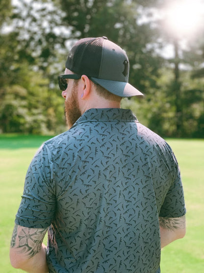 A dark gray performance polo featuring a variety of rifle and pistol icon designs in various sizes and placements.