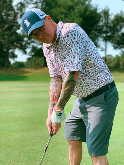 A man putting while wearing the Blue Falcon  "Party Eagle" golf shirt and the Blue Falcon blue and white snapback hat.