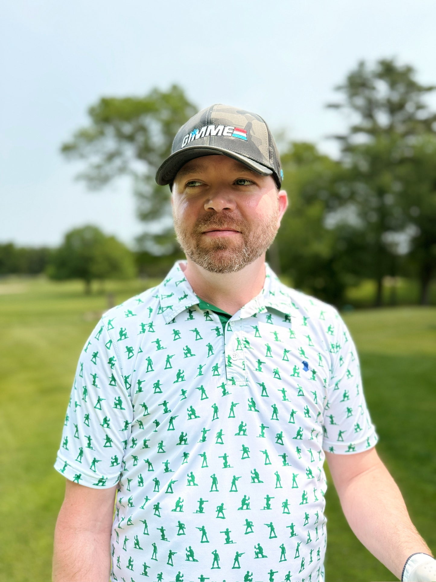 A man wearing a Blue Falcon "Toy Soldier" golf polo nspired by the classic plastic army men we all grew up with, this polo brings childhood nostalgia to the frontlines of modern golf style. He is also wearing a Blue Falcon "Gimmie" hat.